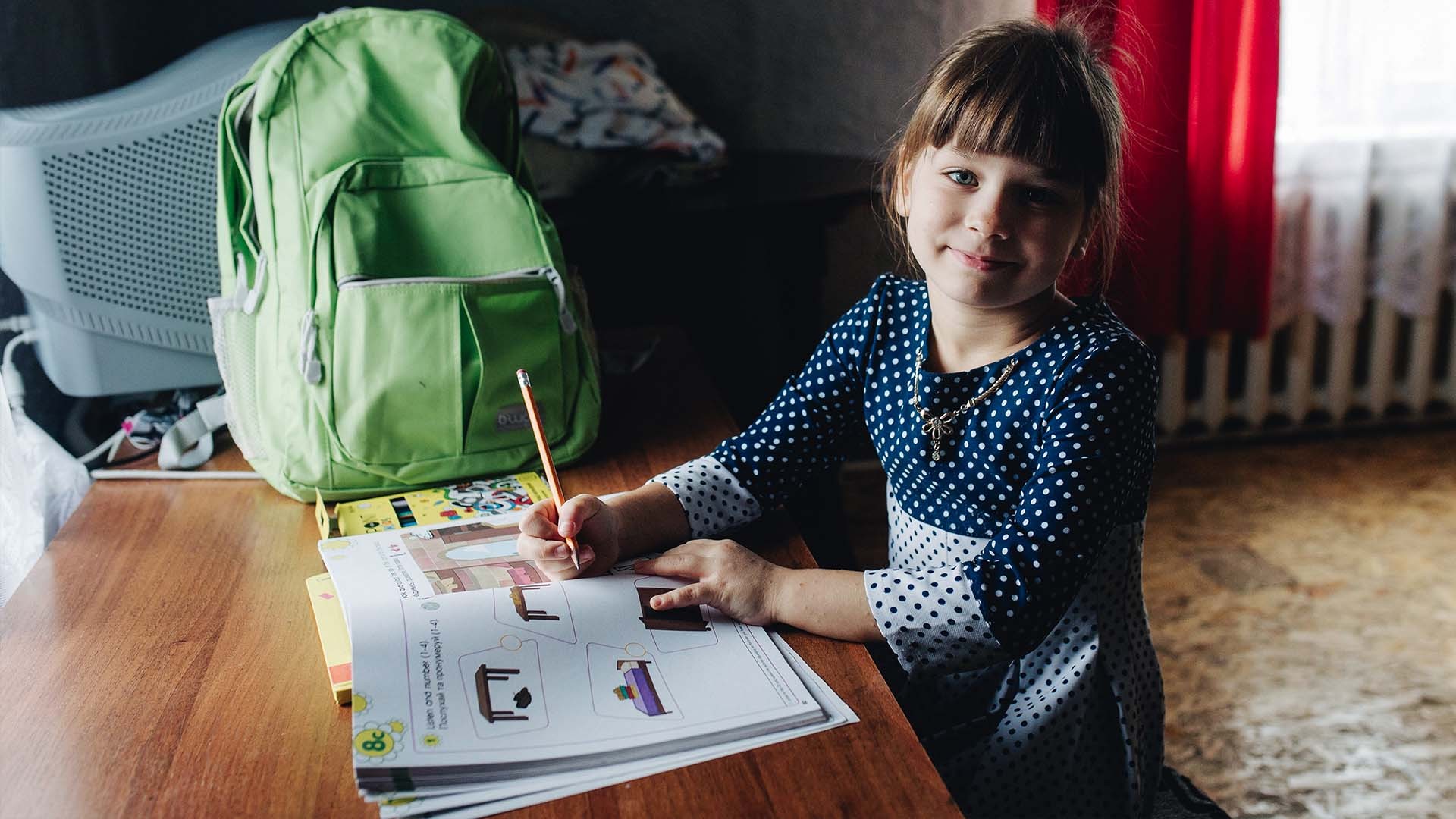 A young girl smiles with new resources for school.