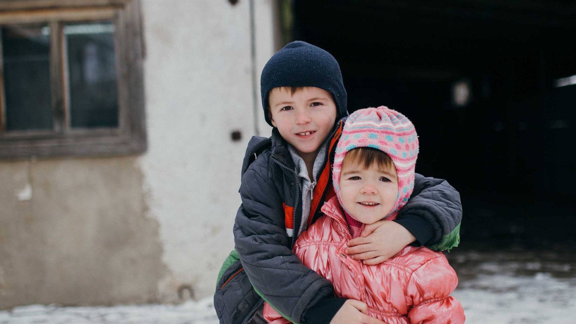 Two children stand in the snow, Ukraine.