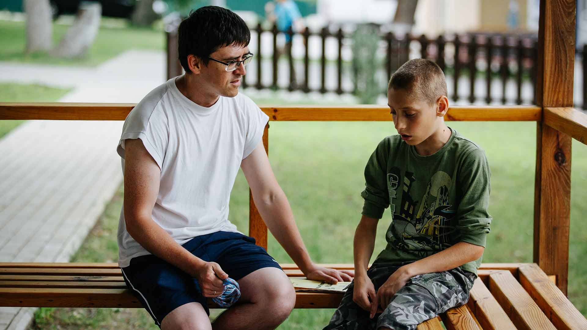 A boy talks with a mentor at summer camp, Ukraine.