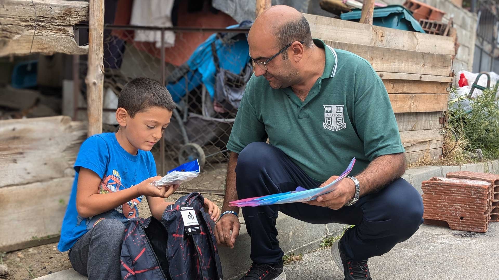 A Mission coordinator gives a boy his new backpack.