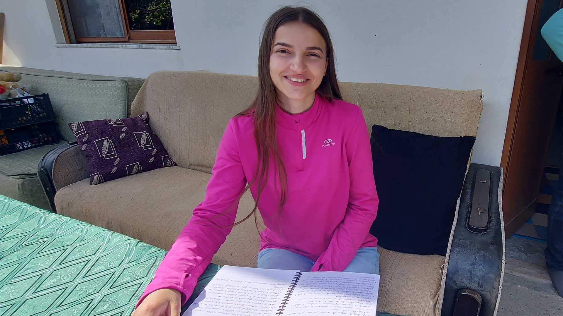 A woman sits studying outside her home, Albania.