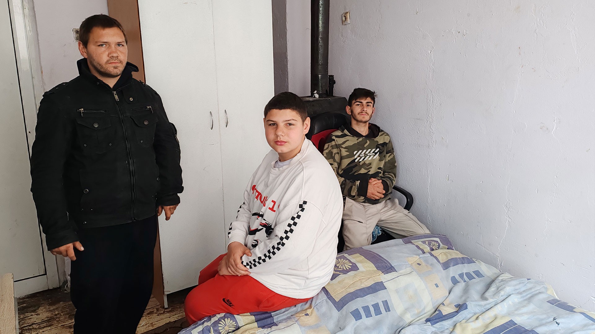 Three brothers sit inside their small house, Bulgaria.