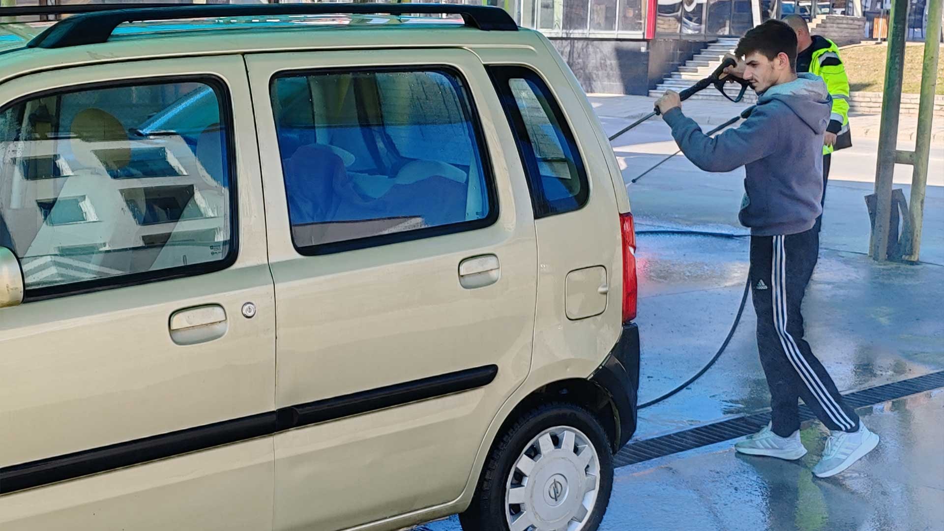 One brother cleans a customer's car.
