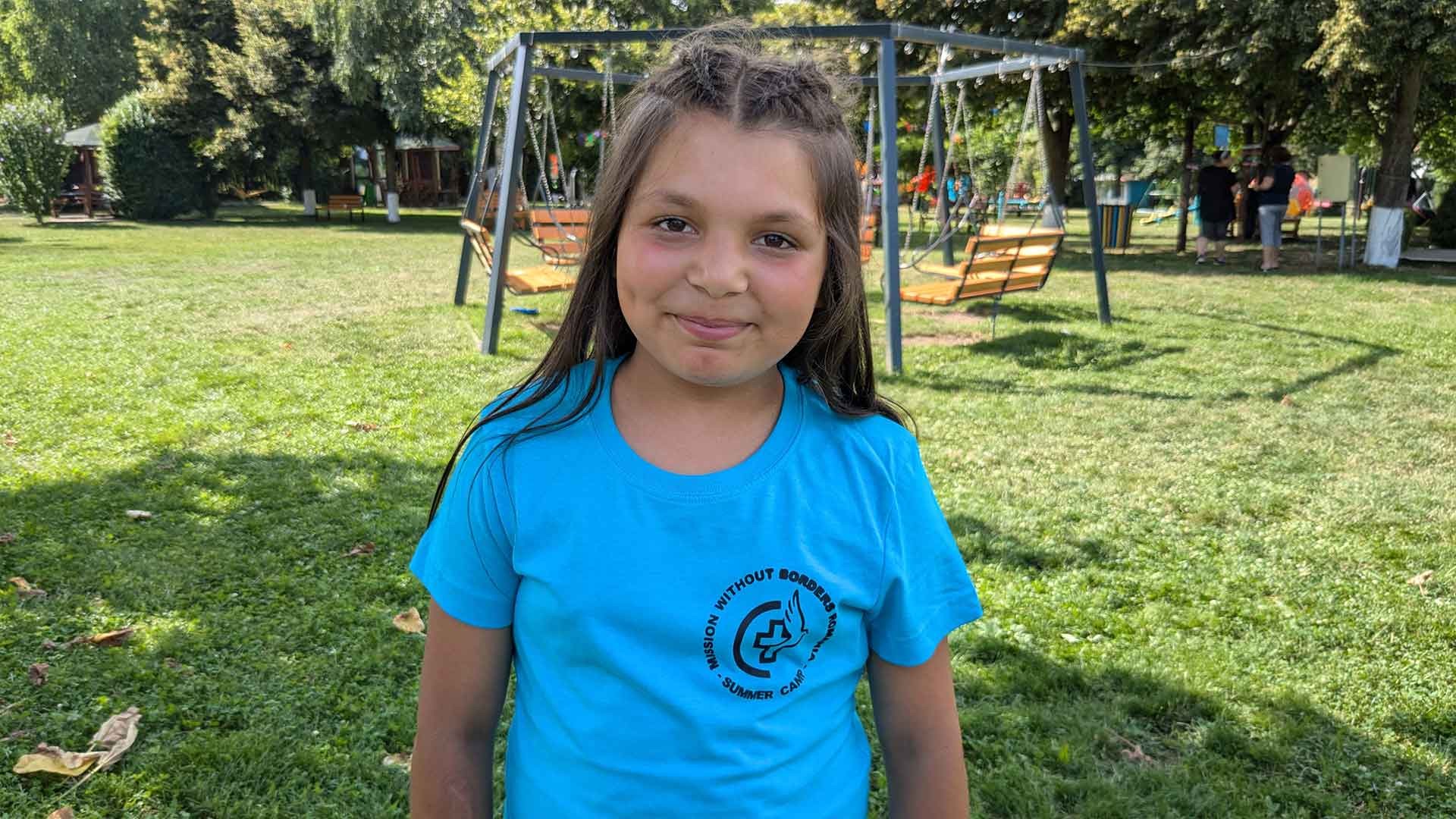 A young girl smiles near a park on summer camp.