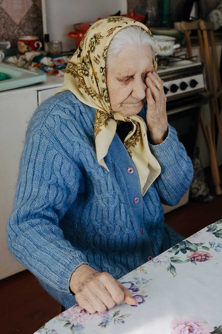 A lady sits in her kitchen.