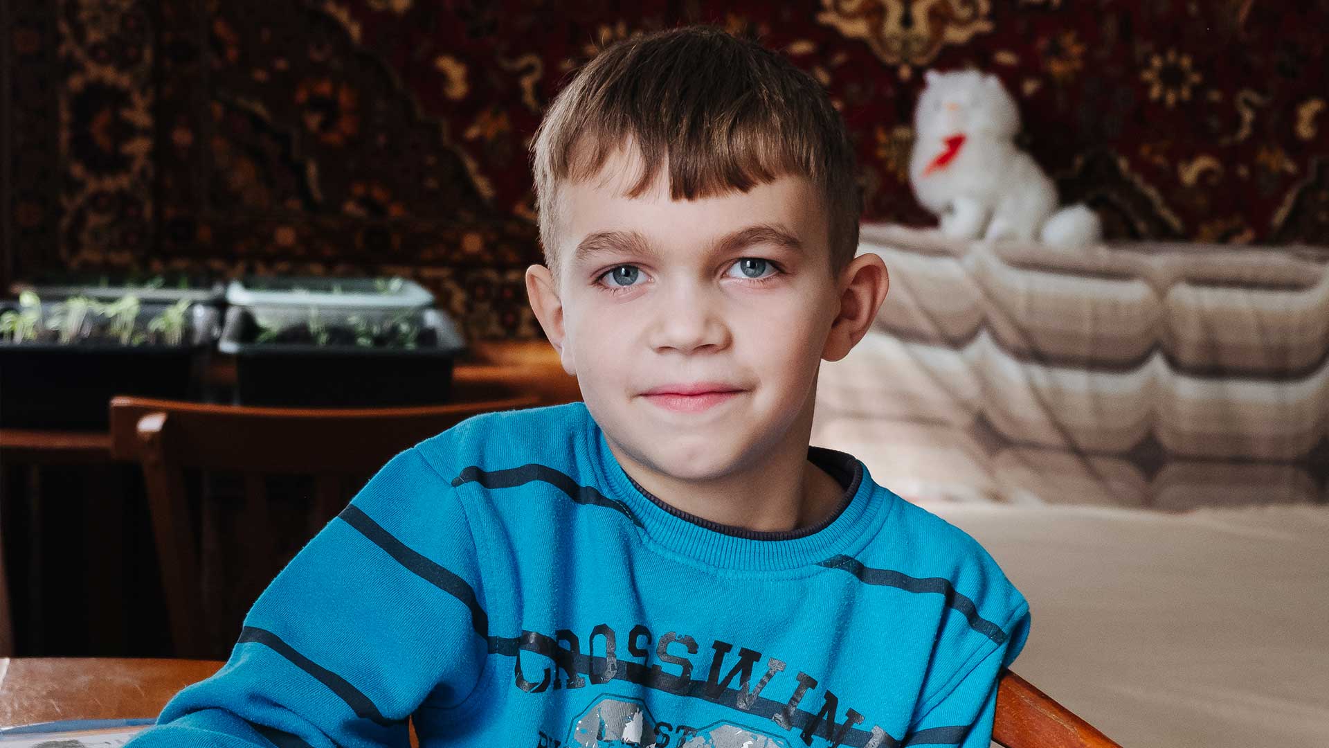 A young boy with trays of seedlings behind him.