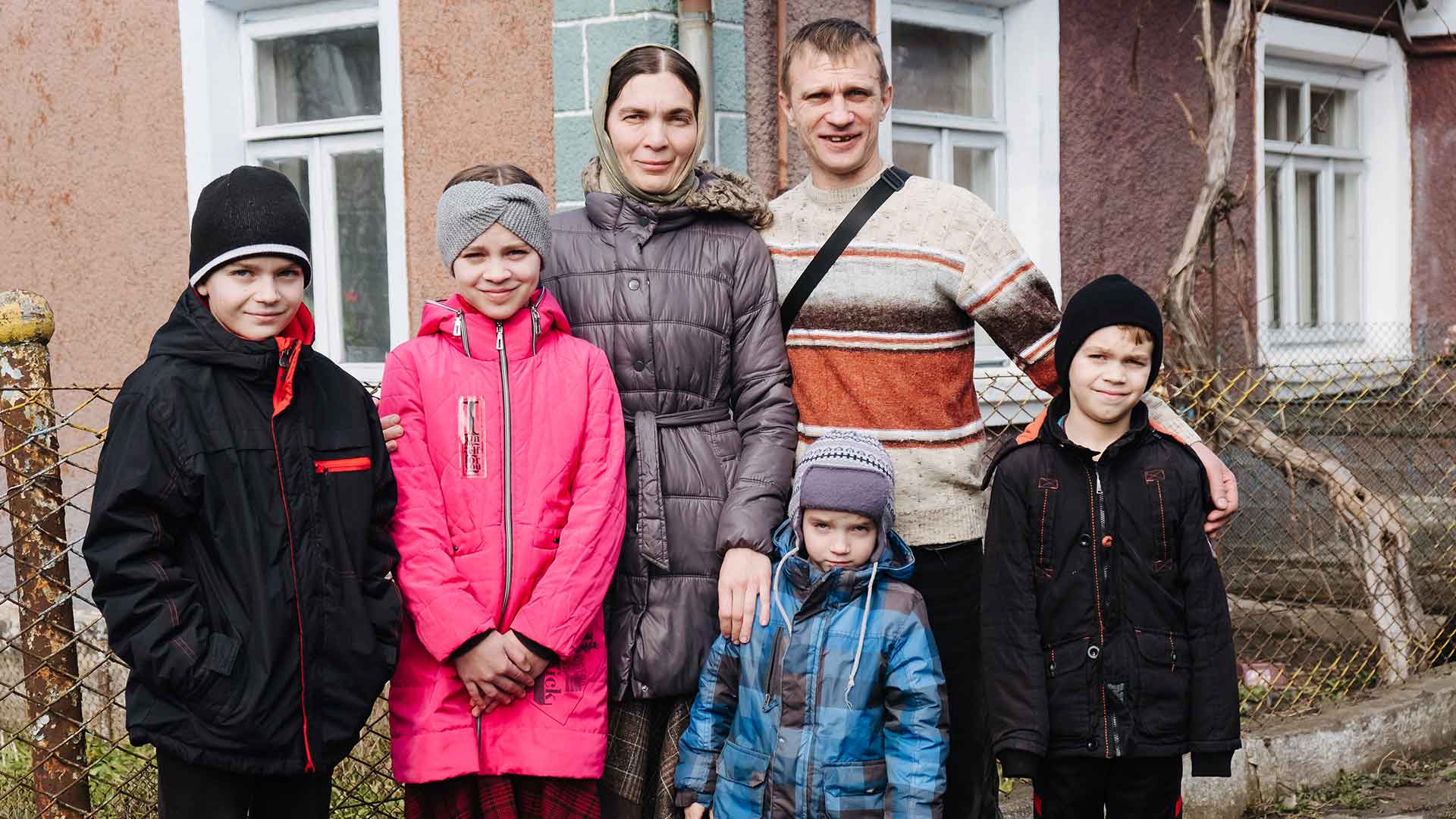 A family stand outside their home.